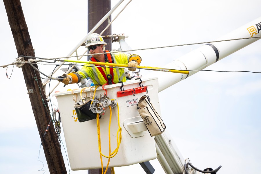 A lineman repairs a power line on Galveston Island on Saturday, July 13, 2024. (AP Photo/Annie Mulligan)