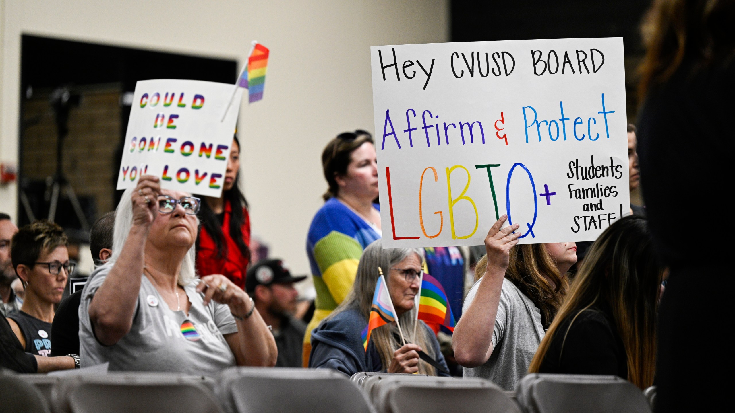 FILE - Parents, students, and staff of Chino Valley Unified School District hold up signs in favor of protecting LGBTQ+ policies at Don Antonio Lugo High School, in Chino, Calif., June 15, 2023. California Gov. Gavin Newsom signed a law Monday, July 15, 2024, barring school districts from passing policies that require schools to notify parents if their child asks to change their gender identification. (Anjali Sharif-Paul/The Orange County Register via AP, File)