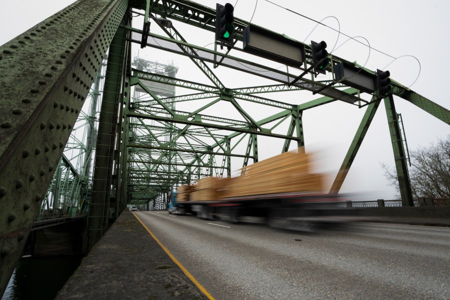 FILE - A logging truck drives on the Interstate 5 bridge that spans the Columbia River and connects Portland, Ore., with southwest Washington state, Feb. 13, 2024. Dozens of aging bridges, including this Interstate 5 bridge, in 16 states will be replaced or improved with the aid $5 billion of federal grants announced Wednesday, July 17, by President Joe Biden's administration as the latest beneficiaries of a massive infrastructure law. (AP Photo/Jenny Kane, File)