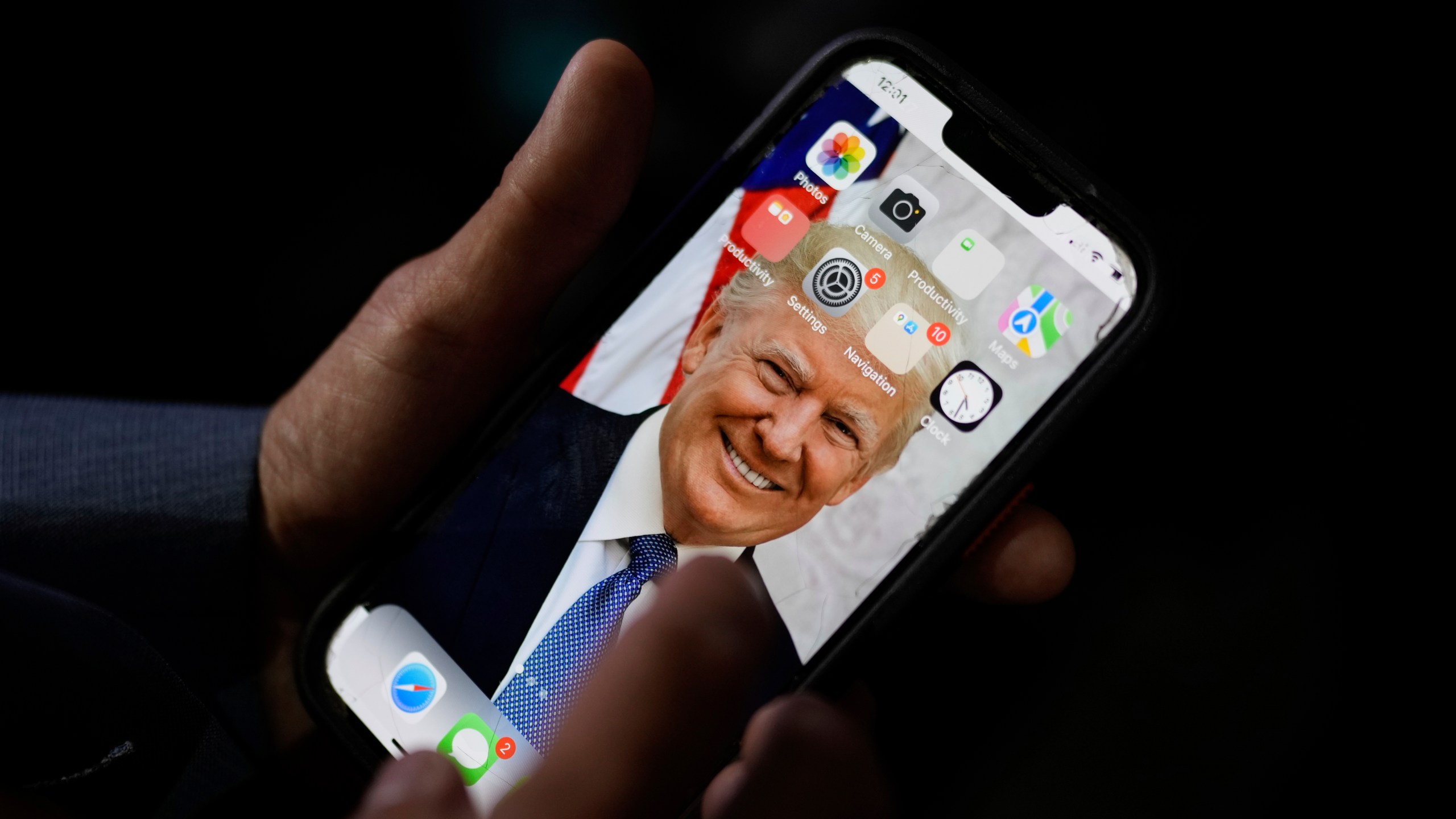 California delegate T. Tran holds his phone with an image of Republican presidential candidate former President Donald Trump as he waits before the Republican National Convention Wednesday, July 17, 2024, in Milwaukee. (AP Photo/Jae C. Hong)