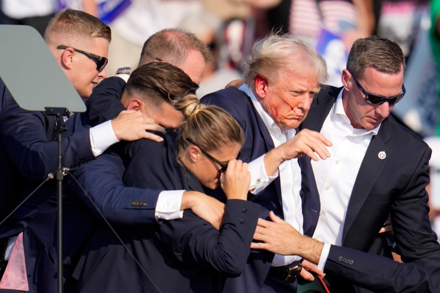 Republican presidential candidate former President Donald Trump is helped off the stage by U.S. Secret Service agents at a campaign event in Butler, Pa., on Saturday, July 13, 2024. (AP Photo/Gene J. Puskar)