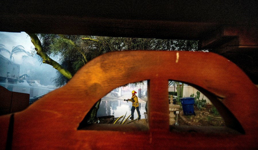 A firefighter hoses down the garage of Noel Piri's home that was destroyed by the Hawarden Fire in Riverside, Calif., on Sunday, July 21, 2024. (Terry Pierson/The Orange County Register via AP)