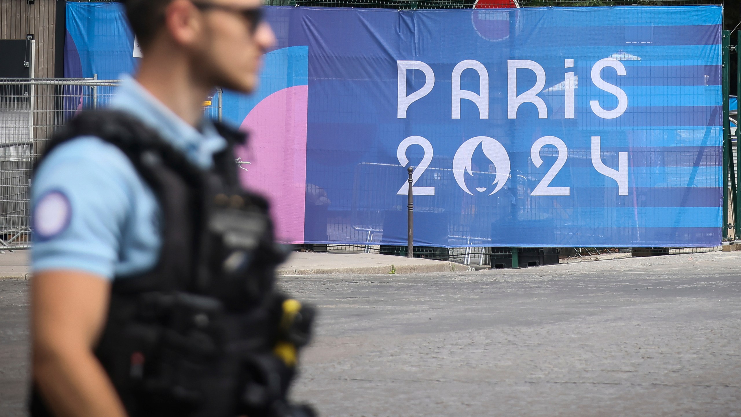 FILE - A police officer walks past a Paris Olympics canvas at the 2024 Summer Olympics, Saturday, July 20, 2024, in Paris, France. Three days before the start of the Olympics, France's Interior Minister has hailed the country’s law enforcement for their hard work in making the Paris Games safe for 10,500 athletes and millions of visitors. (AP Photo/Thomas Padilla, File)