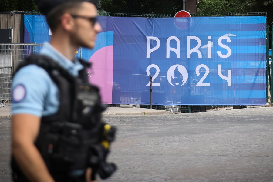 FILE - A police officer walks past a Paris Olympics canvas at the 2024 Summer Olympics, Saturday, July 20, 2024, in Paris, France. Three days before the start of the Olympics, France's Interior Minister has hailed the country’s law enforcement for their hard work in making the Paris Games safe for 10,500 athletes and millions of visitors. (AP Photo/Thomas Padilla, File)