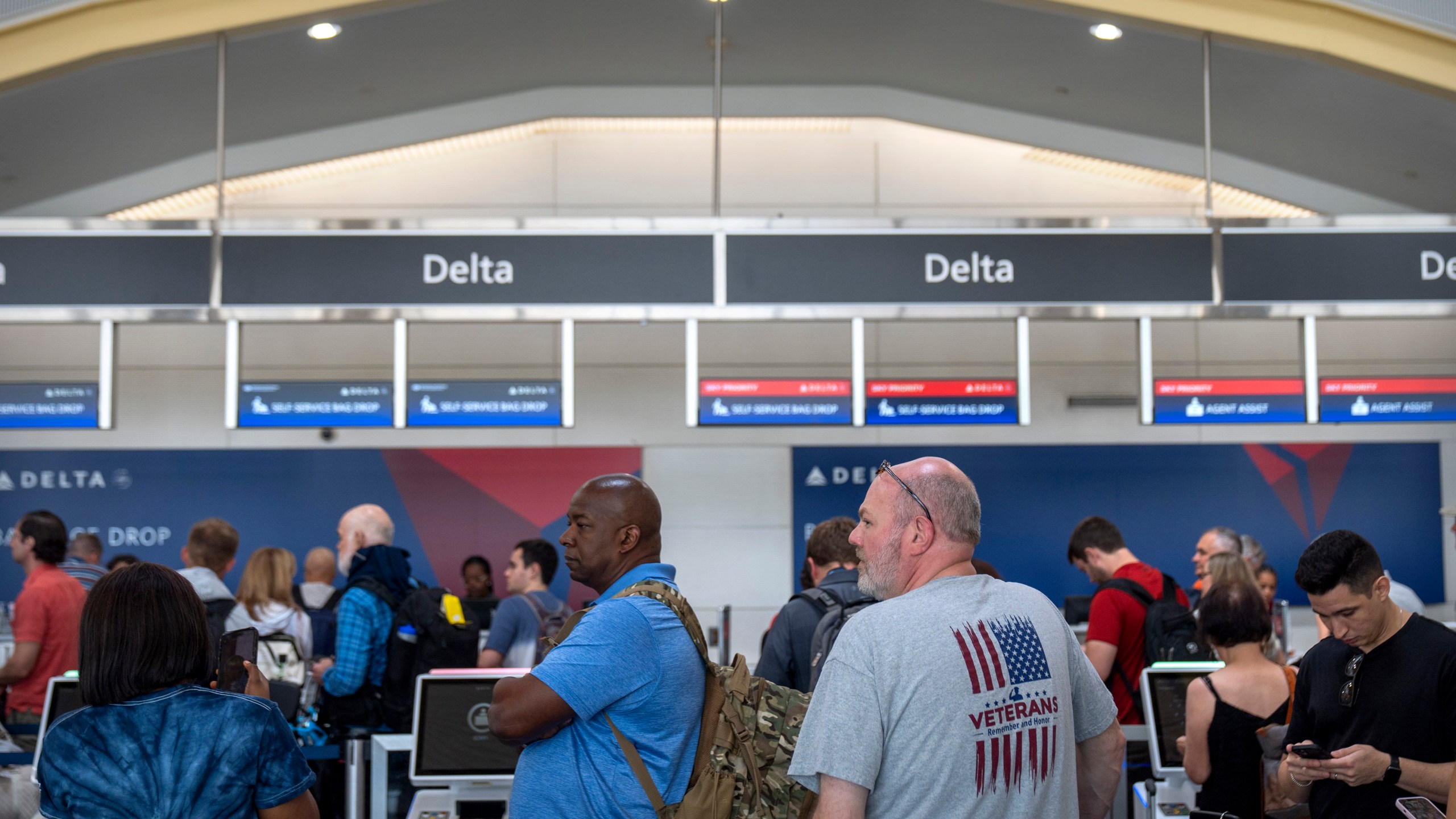 Travelers stand in line at a Delta Air Lines counter at Reagan National Airport on Friday, July 19, 2024, in Arlington, Va. A global technology outage caused by a faulty software update grounded flights, knocked banks and media outlets offline, and disrupted hospitals, small businesses and other services on Friday, highlighting the fragility of a digitized world dependent on just a handful of providers. (AP Photo/Mark Schiefelbein)