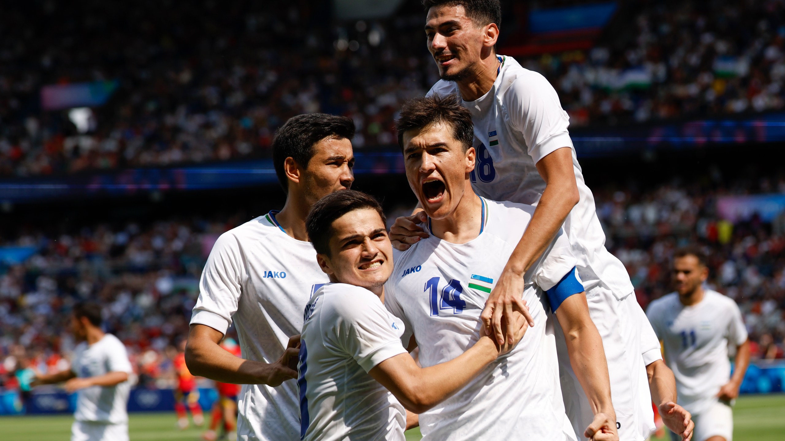 Uzbekistan's Eldor Shomurodov, centre, celebrates with teammates after scoring his team's first goal during the men's group C match between Uzbekistan and Spain at the Parc des Princes during the 2024 Summer Olympics, Wednesday, July 24, 2024, in Paris, France. (AP Photo/Aurelien Morissard)