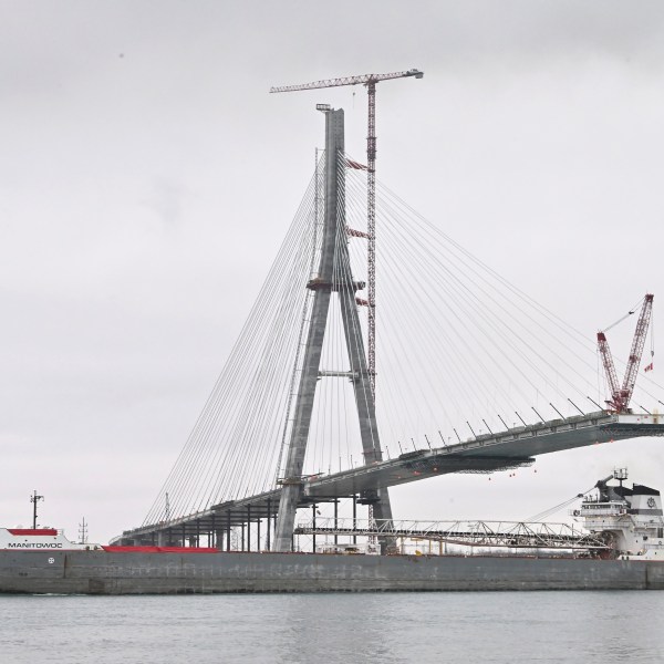 FILE - The freighter Manitowoc makes its way down the Detroit River past continuing construction on the Canadian span of the Gordie Howe International Bridge, Dec. 29, 2023, in Detroit. On Wednesday, July 24, 2024, workers linked the U.S. and Canadian sides of the new Gordie Howe International Bridge spanning the Detroit River, a major step in bringing the monumental project to completion. (Daniel Mears/Detroit News via AP, File)