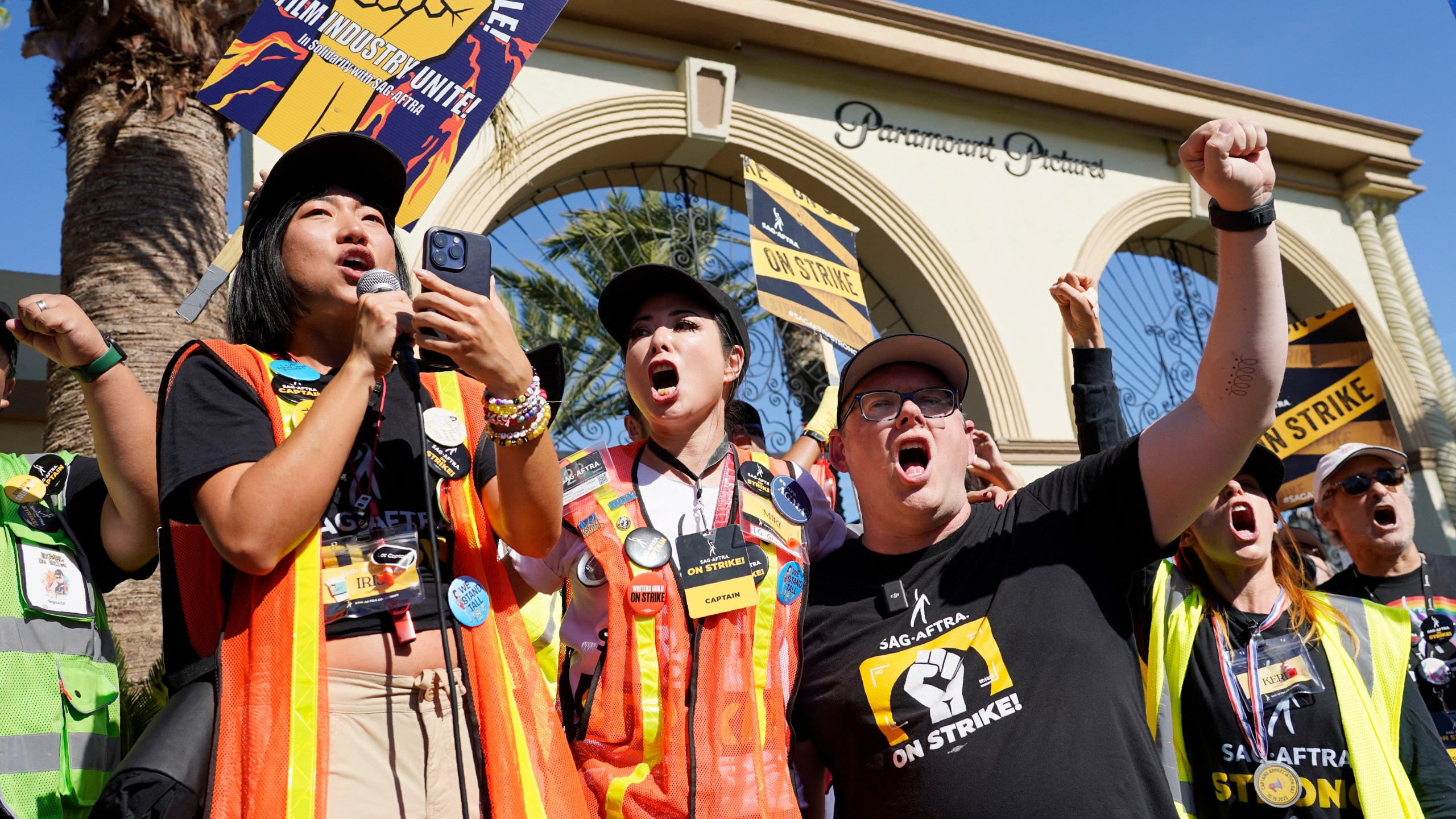 FILE - SAG-AFTRA captains Iris Liu, left, and Miki Yamashita, center, and SAG-AFTRA chief negotiator Duncan Crabtree-Ireland lead a cheer for striking actors outside Paramount Pictures studio, Nov. 3, 2023, in Los Angeles. Hollywood's video game performers voted to go on strike Thursday, July 25, 2024, throwing part of the entertainment industry into another work stoppage after talks for a new contract with major game studios broke down over artificial intelligence protections. (AP Photo/Chris Pizzello, File)