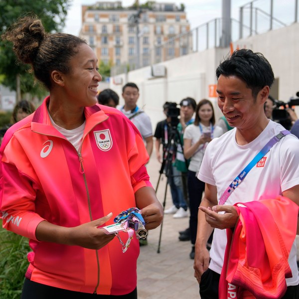 Naomi Osaka, of Japan, left, talks to a journalist after her practice session at the 2024 Summer Olympics, Thursday, July 25, 2024, in Paris, France. (AP Photo/Andy Wong)