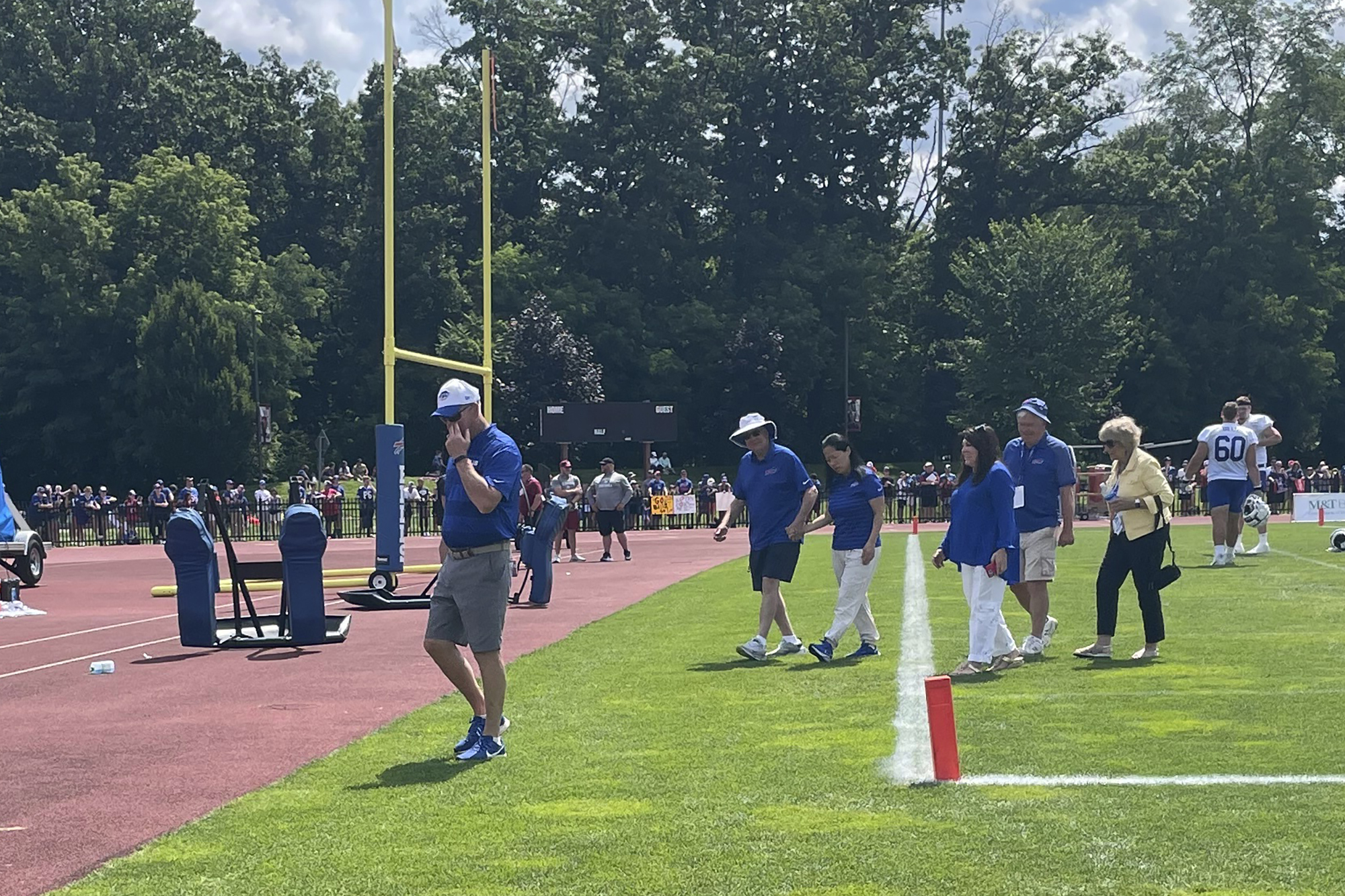 Buffalo Bills owner Terry Pegula holds his wife Kim Pegula's hand as he escorts her off the field after she met with the players in the end zone following the end of training camp in Pittsford, N.Y., Friday, July 26, 2024. (AP Photo/John Wawrow)