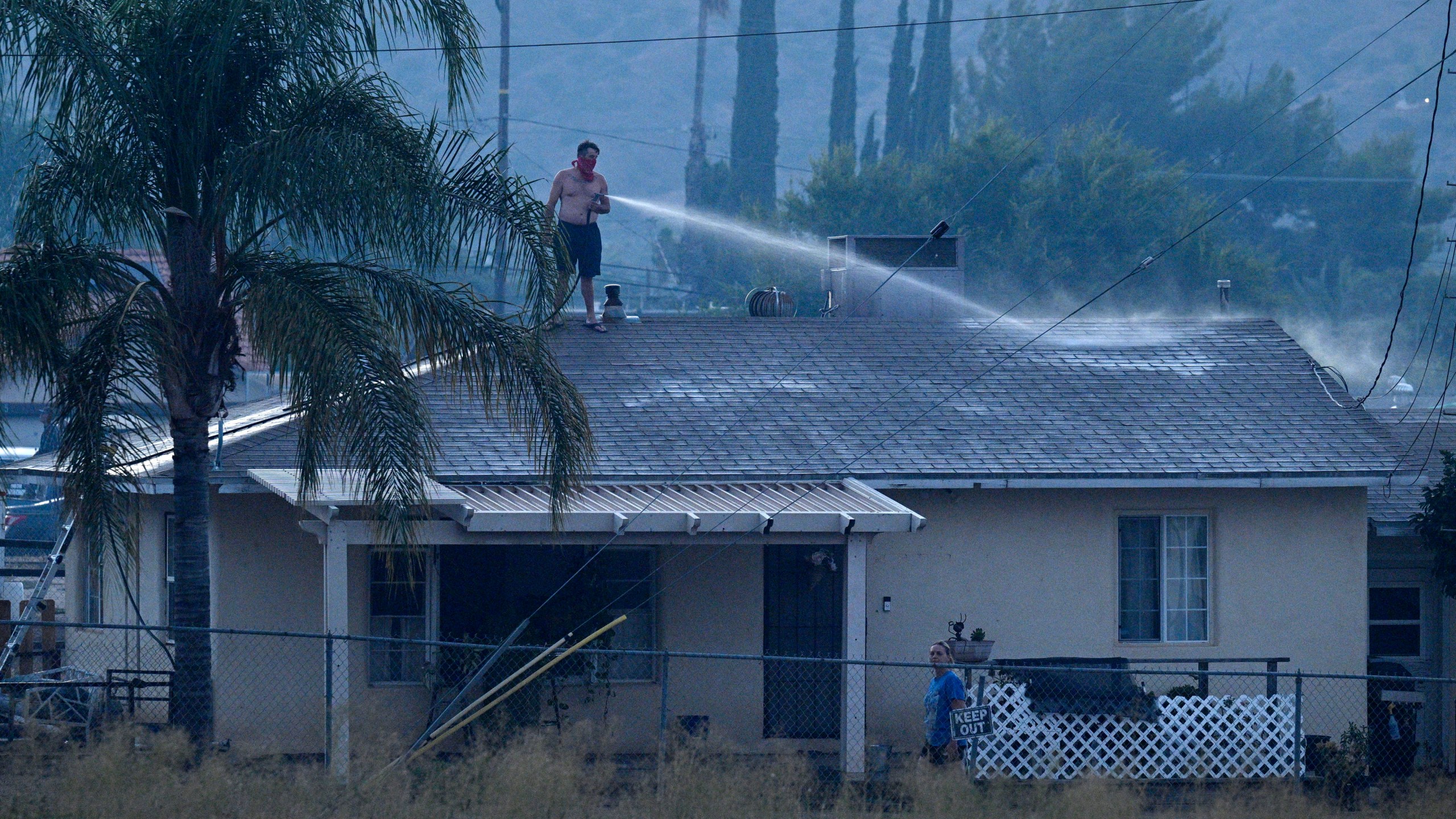 A home owner keeps his roof wet to keep embers from taking hold as Cal Fire Riverside County firefighters battle the Macy Fire in Lake Elsinore, Calif., on Thursday, July 25, 2024. (Terry Pierson/The Orange County Register via AP)