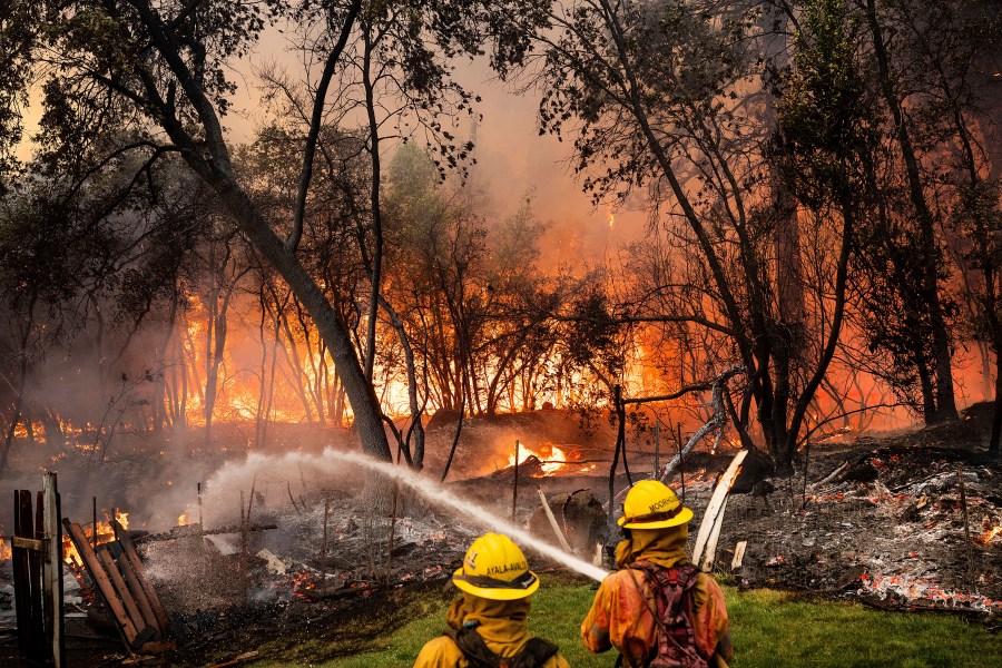 Firefighters spray water while battling the Park Fire in the Cohasset community of Butte County, Calif., on Thursday, July 25, 2024. The crew was able to keep flames from reaching the mobile home they were protecting. (AP Photo/Noah Berger)