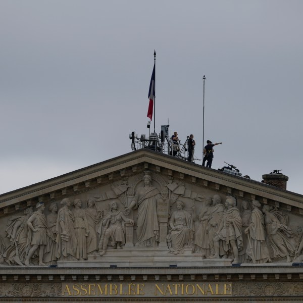 Security staff stand atop the roof of the National Assembly in Paris, France, ahead of the opening ceremony of the 2024 Summer Olympics, Friday, July 26, 2024. (AP Photo/Charlie Riedel)