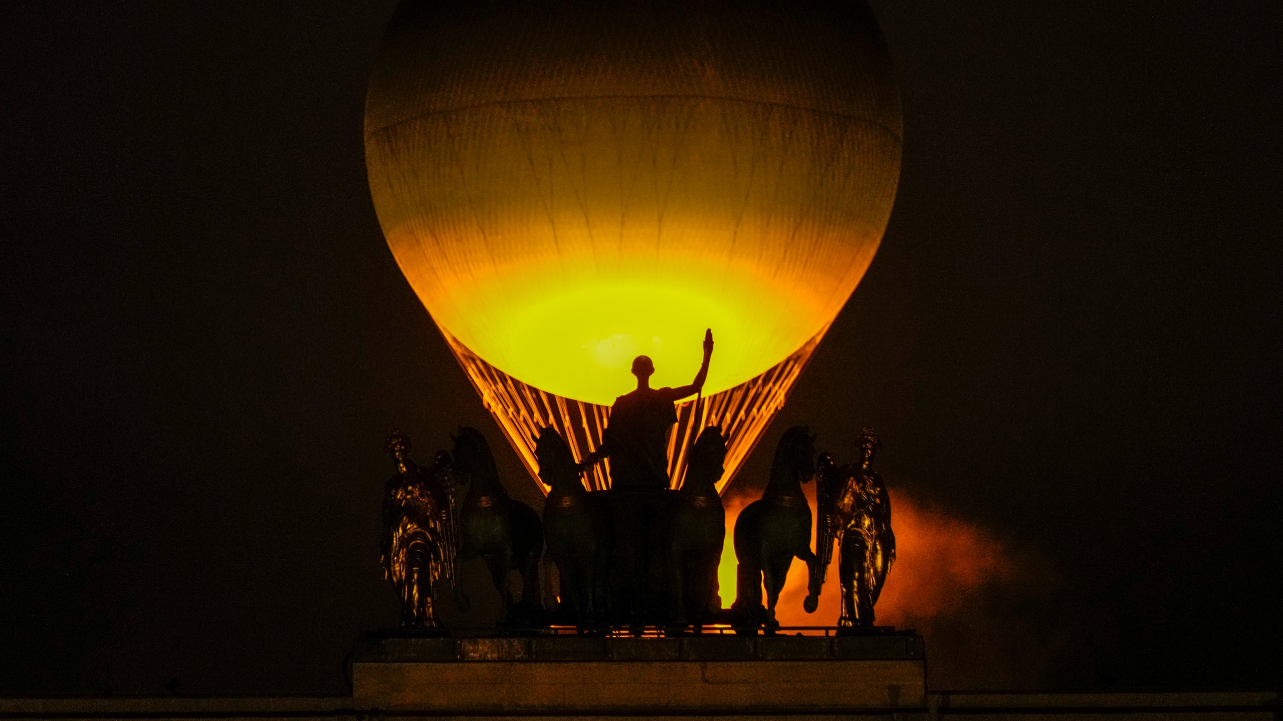 The Olympic Flame rises on a balloon above a statue after being lit in Paris, France, during the opening ceremony of the 2024 Summer Olympics, Friday, July 26, 2024. (AP Photo/Francisco Seco)