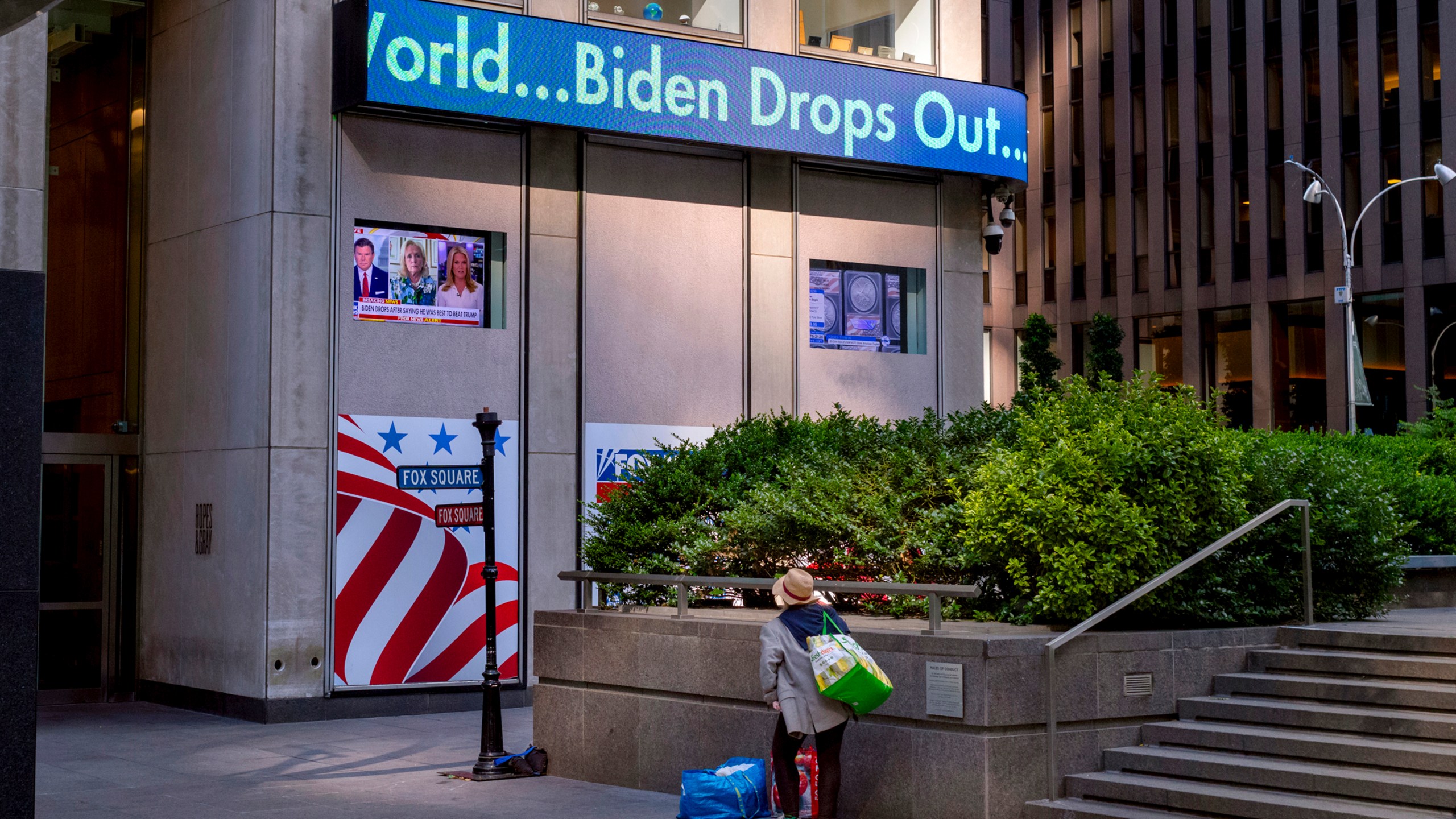 FILE - A passerby watches a news crawl appears on the side of the Fox News building in New York, Sunday, July 21, 2024, in the wake of President Joe Biden dropping out of the presidential race. Biden's announcement was a startling example of how fast and how far word spreads in today's always-connected world. (AP Photo/Craig Ruttle, File)