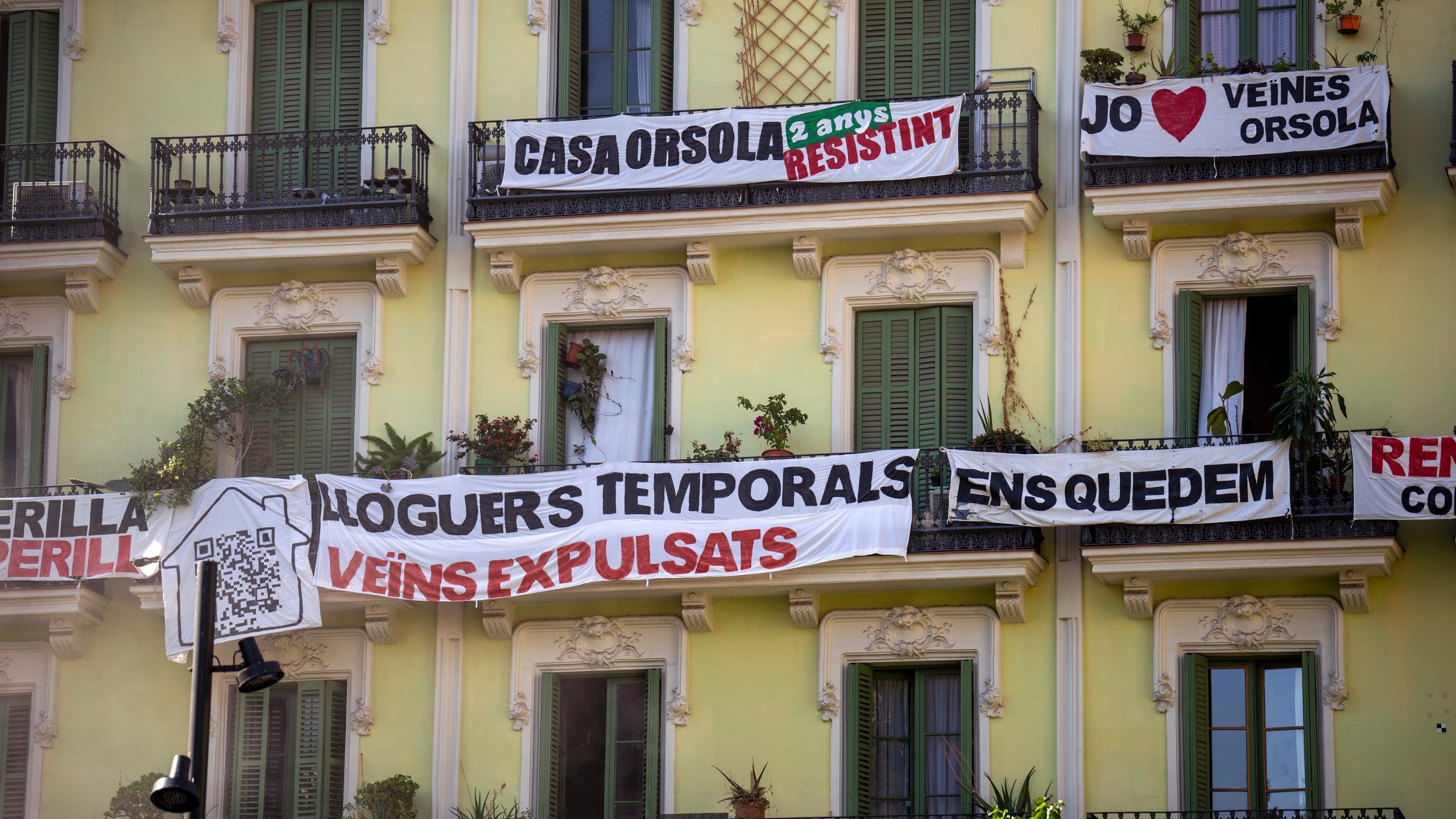 A block of flats, which is under threat of eviction, is photographed in downtown Barcelona, Spain, Wednesday, July 10, 2024. Barcelona City Hall announced last month that it would not renew any tourist apartment licenses after they expire in 2028. the banner reads in Catalan: "temporary rental housing: neighbours evicted". (AP Photo/Emilio Morenatti)