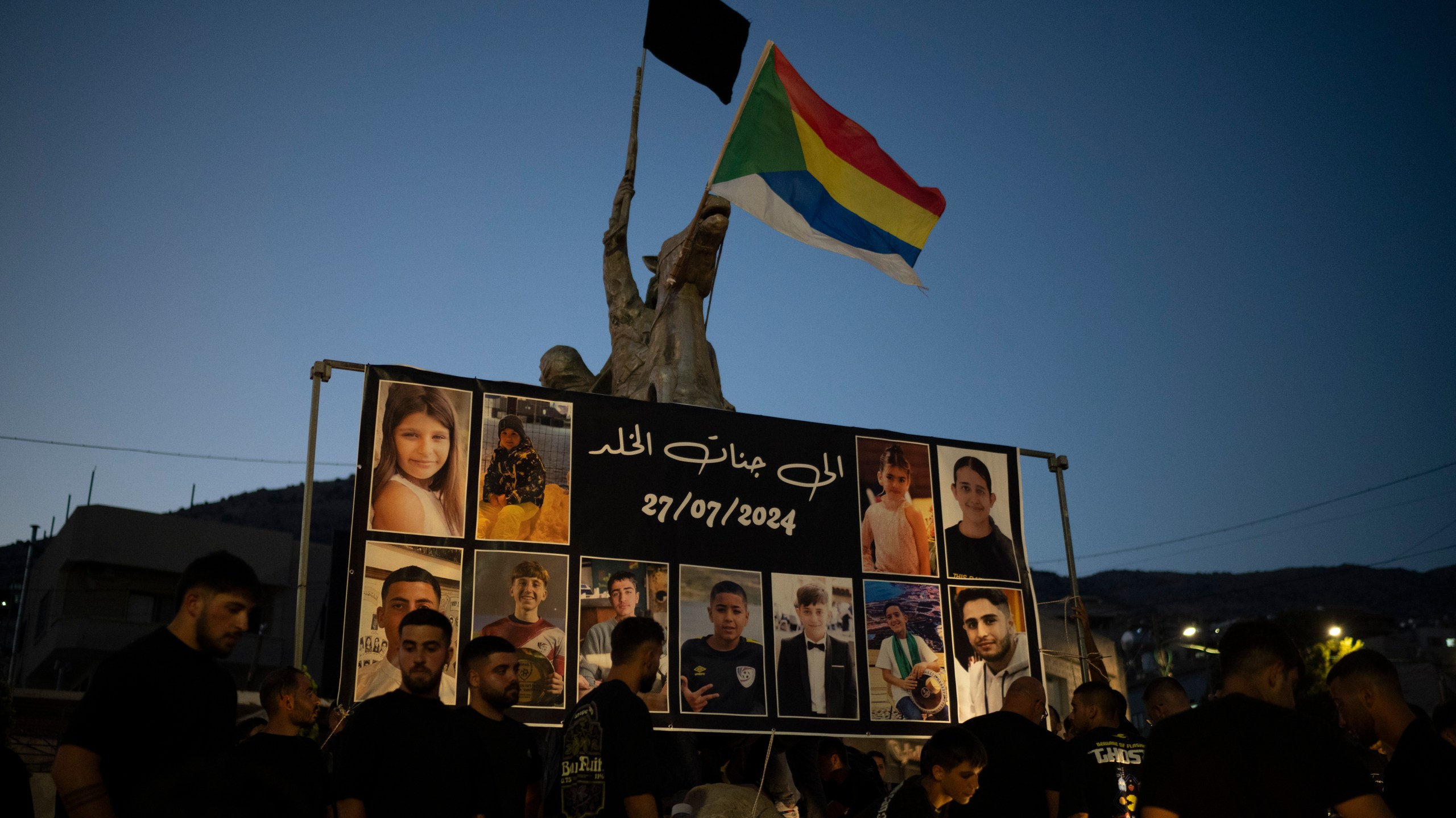 Photos of the children and teens killed in a rocket strike at a soccer field, are displayed at a roundabout as people light candles in their memories, at the village of Majdal Shams, in the Israeli-annexed Golan Heights, Sunday, July 28, 2024. A rocket strike at a soccer field in the village has killed at least 12 children and teens. It's the deadliest strike on an Israeli target along the country's northern border since the fighting between Israel and the Lebanese militant group Hezbollah began. (AP Photo/Leo Correa)