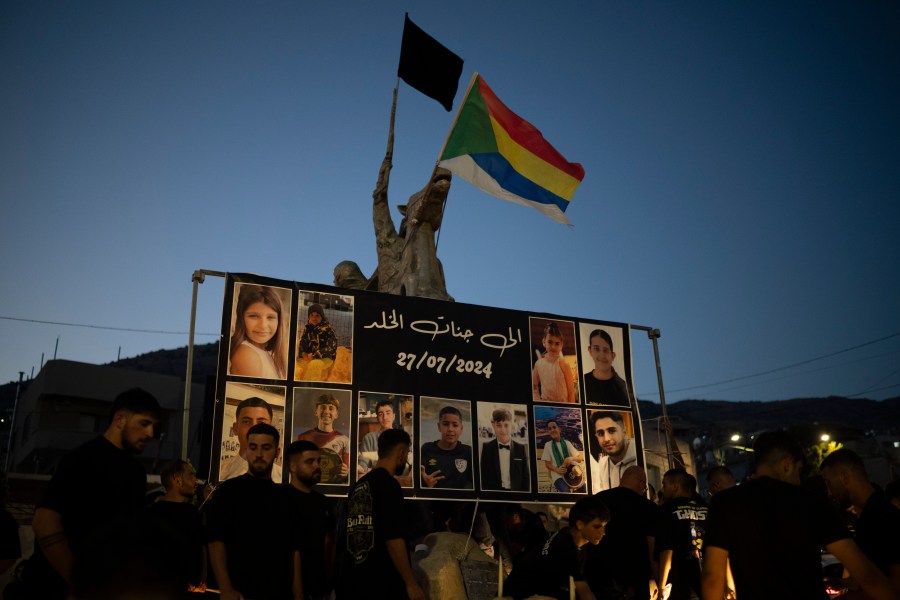 Photos of the children and teens killed in a rocket strike at a soccer field, are displayed at a roundabout as people light candles in their memories, at the village of Majdal Shams, in the Israeli-annexed Golan Heights, Sunday, July 28, 2024. A rocket strike at a soccer field in the village has killed at least 12 children and teens. It's the deadliest strike on an Israeli target along the country's northern border since the fighting between Israel and the Lebanese militant group Hezbollah began. (AP Photo/Leo Correa)