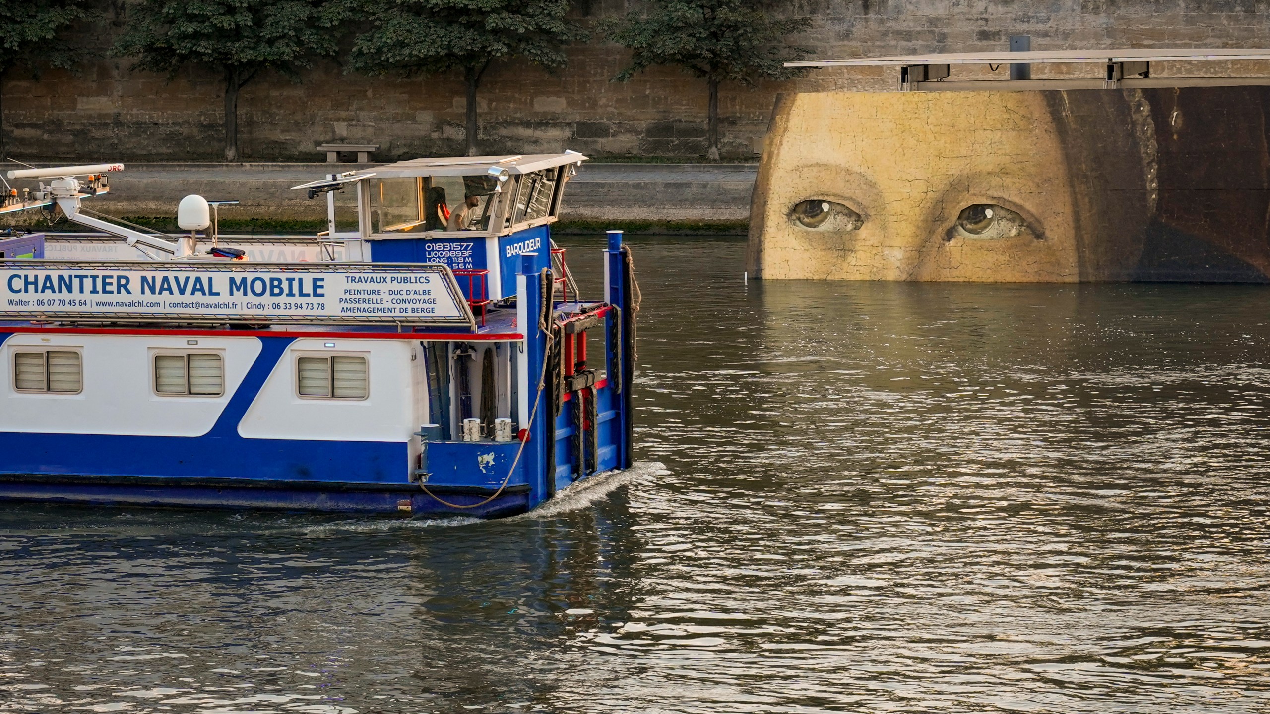 A ship sails past reproductions of artworks decorating the banks of the River Seineat the 2024 Summer Olympics, Tuesday, July 30, 2024, in Paris, France. The men's Olympic triathlon has been postponed over concerns about water quality in Paris' Seine River, where the swimming portion of the race was supposed to take place. (AP Photo/ Dar Yasin)