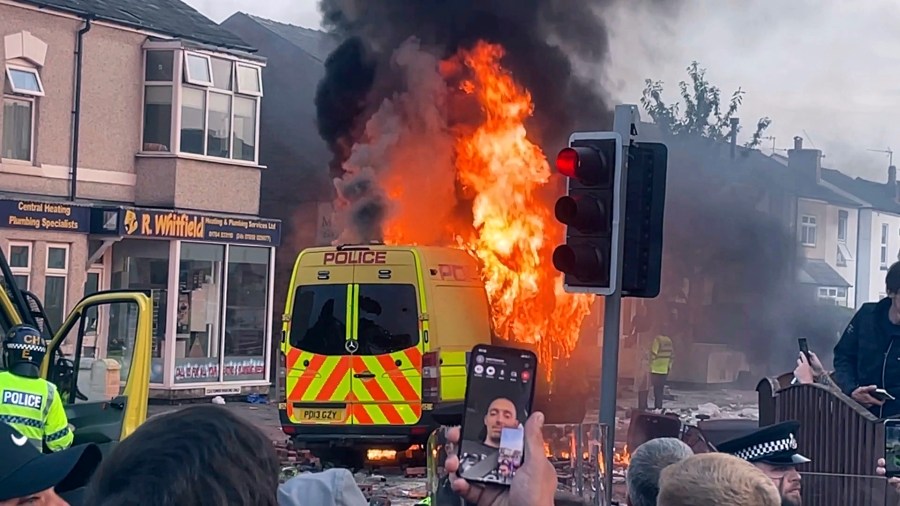 A police van buns as and unruly crowd clashed with police, Tuesday, July 30, 2024, in Southport, northwest England, near where three girls were stabbed to death in a dance class the day before. The violence erupted shortly after a peaceful vigil was attended by hundreds in the center of Southport to mourn the 13 victims of the stabbings, including seven still in critical condition. (Richard McCarthy/PA via AP)