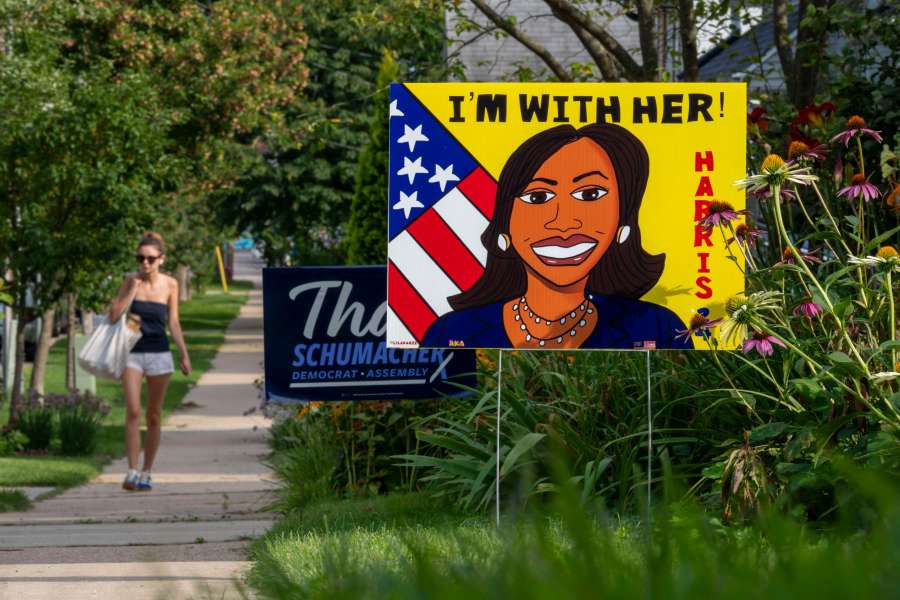 A pedestrian walks along the sidewalk past a sign in support of Kamala Harris on Tuesday, July 30, 2024, in Madison, Wis. (AP Photo/Kayla Wolf)