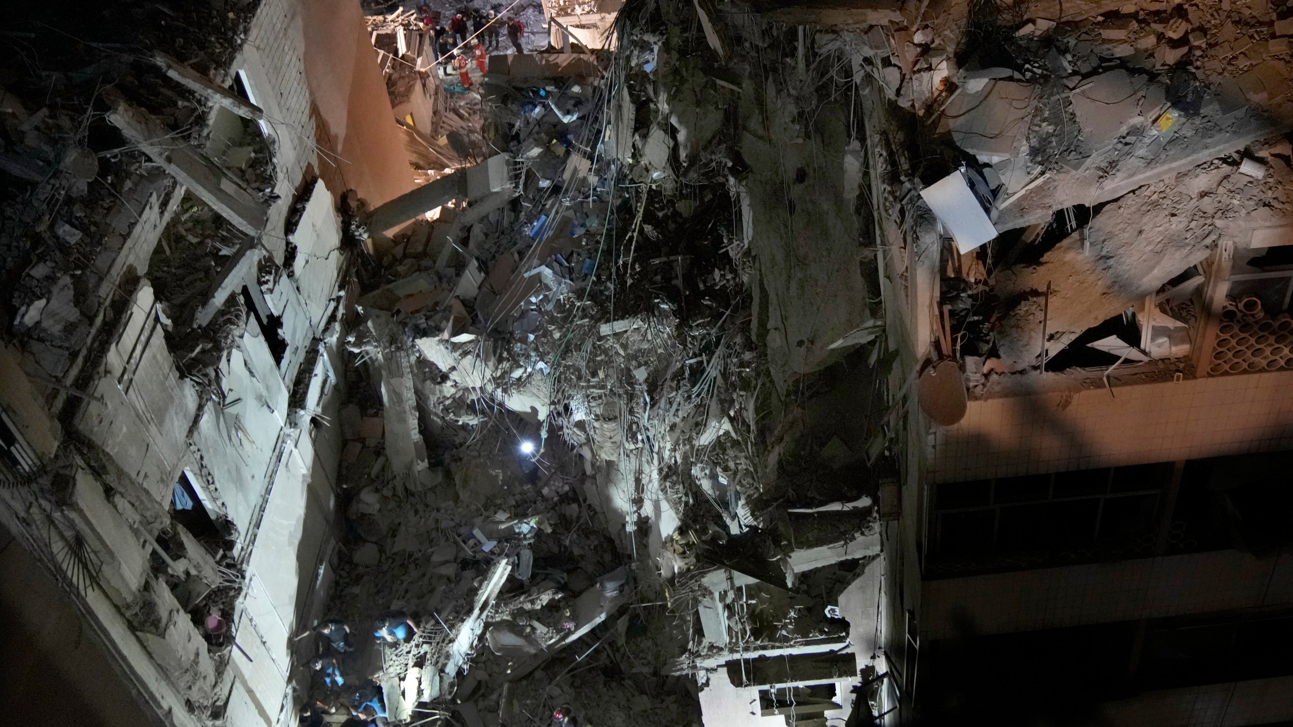 Civil defence workers check for victims between the wreckage of destroyed buildings that were hit by an Israeli airstrike in the southern suburbs of Beirut, Lebanon, Tuesday, July 30, 2024. An Israeli airstrike hit Hezbollah's stronghold south of Beirut Tuesday evening causing damage, a Hezbollah official and the group's TV station said. (AP Photo/Hussein Malla)