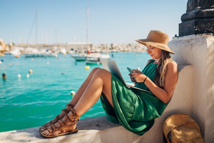 Woman writes a text message on a mobile phone while sitting not far from the sea.