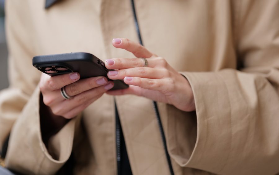 Woman with pink manicure texts on a phone.