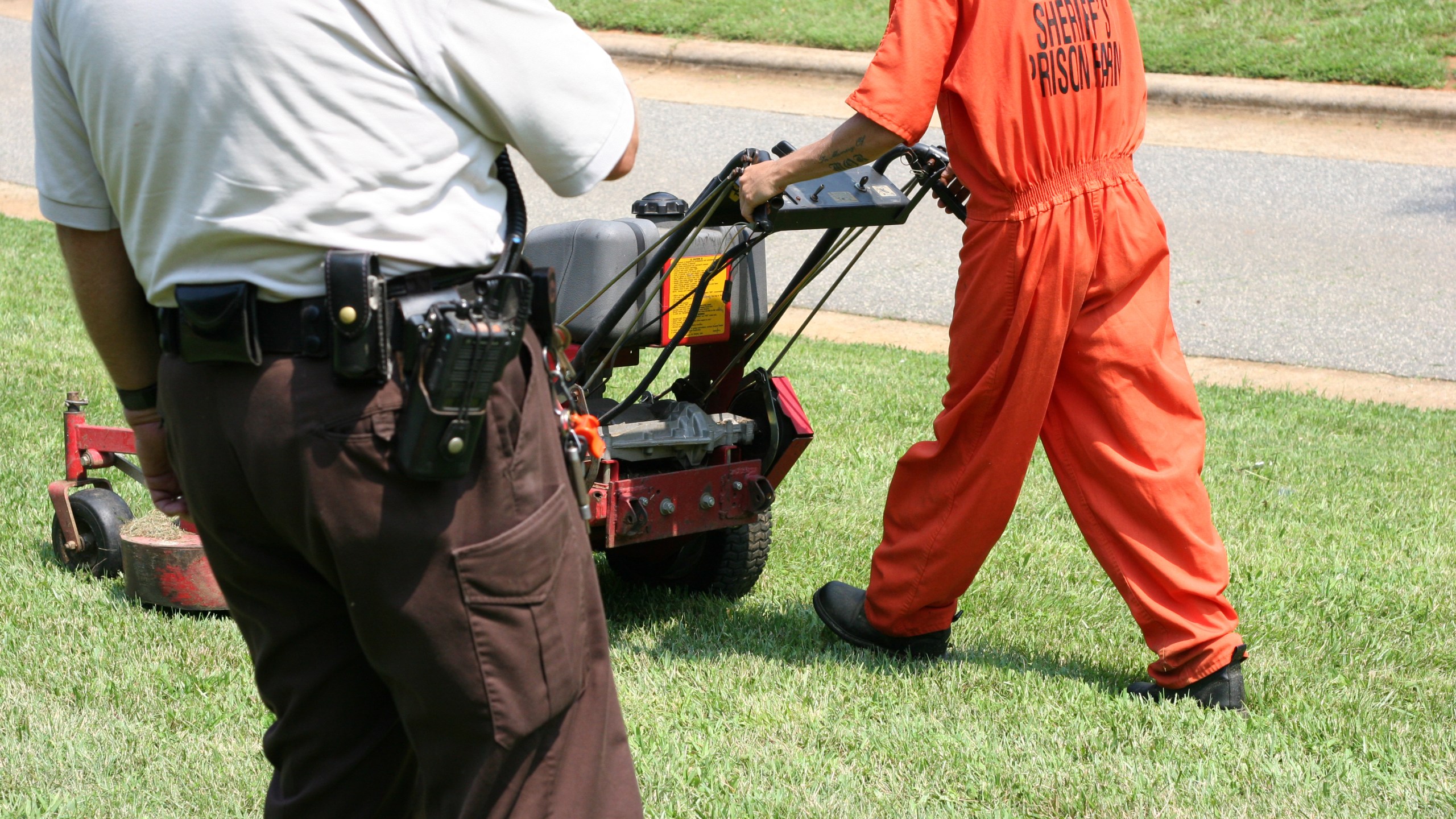 Prisoner working while law enforcement officer keeps watch.