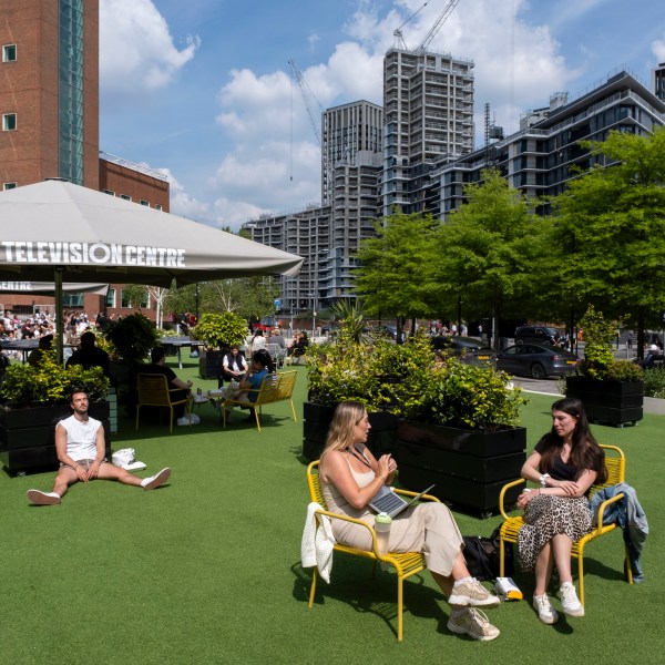 Young workers hanging out on the fake grass in the sunshine outside BBC Television Centre