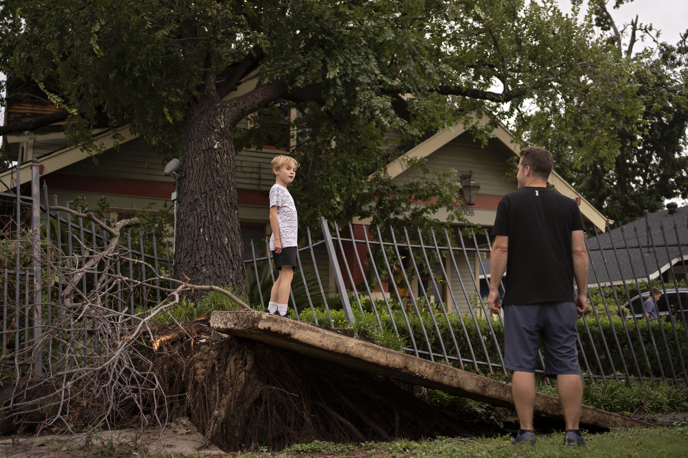 Nick Jensen, right, and his son, Maverick, left, look at a felled tree at their Air BnB in the wake of Hurricane Beryl.