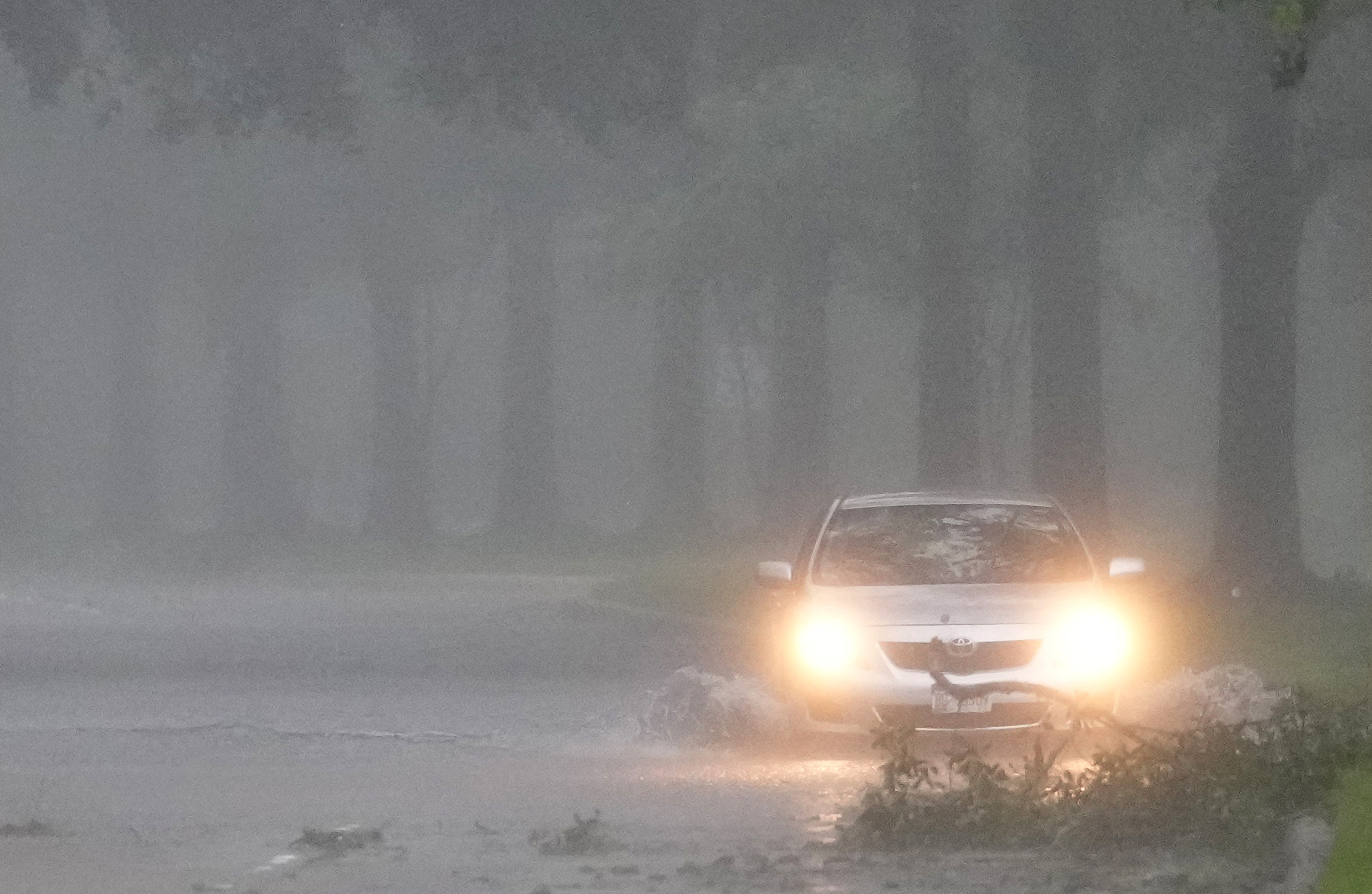 A vehicle maneuvers through high water and debris on Cypresswood Dr. during Hurricane Beryl Monday, July 8, 2024, in Spring.