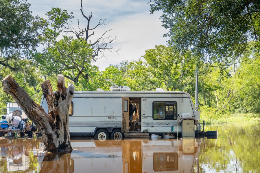 A person prepares to close the door of their mobile home as it is surrounded by floodwater after Hurricane Beryl swept through the area on July 08, 2024 in Brazoria, Texas.