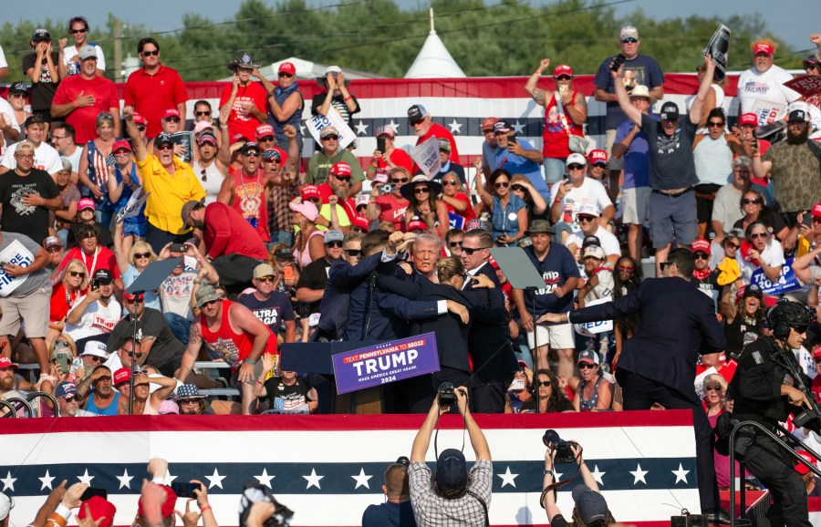 Donald Trump is seen with blood on his face surrounded by secret service agents as he is taken off the stage at a campaign event in Butler, Pennsylvania