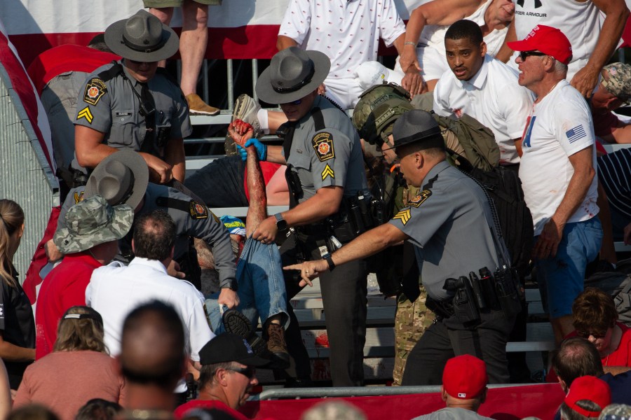 A person is removed by state police from the stands after guns were fired at Republican candidate Donald Trump.