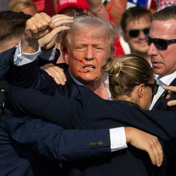 Donald Trump is seen with blood on his face surrounded by Secret Service agents following an assassination attempt.