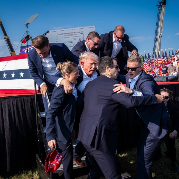 Secret Service agents rush Donald Trump offstage.