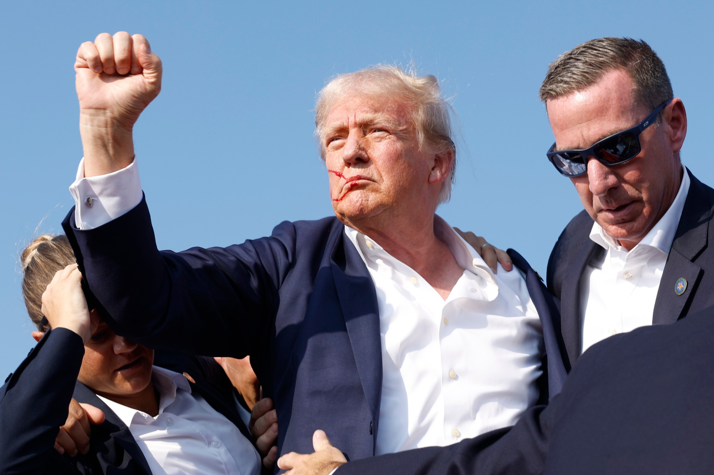 Holding a fist in the air, former President Donald Trump is rushed offstage during a rally on July 13, 2024 in Butler, Pennsylvania