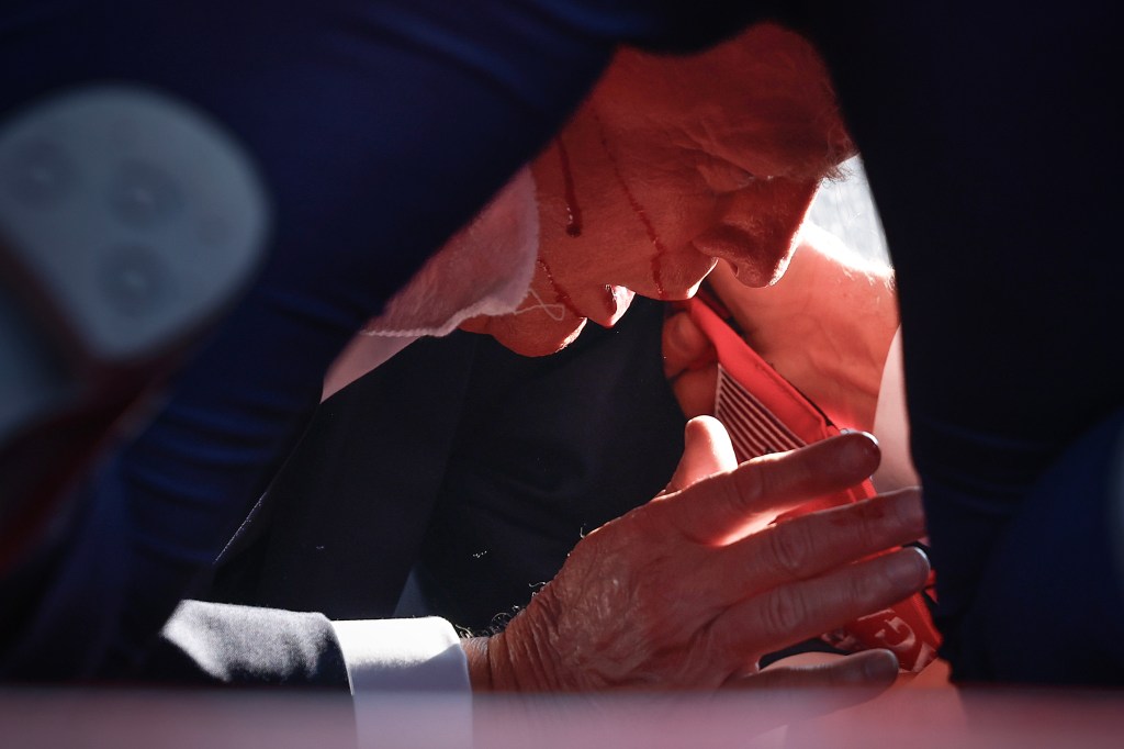 An injured Donald Trump on the ground shielded by Secret Service.