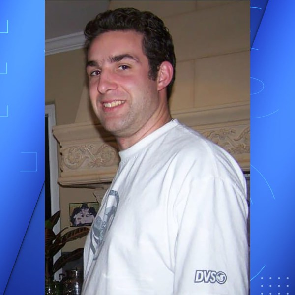 A dark haired man in a white tee shirt.