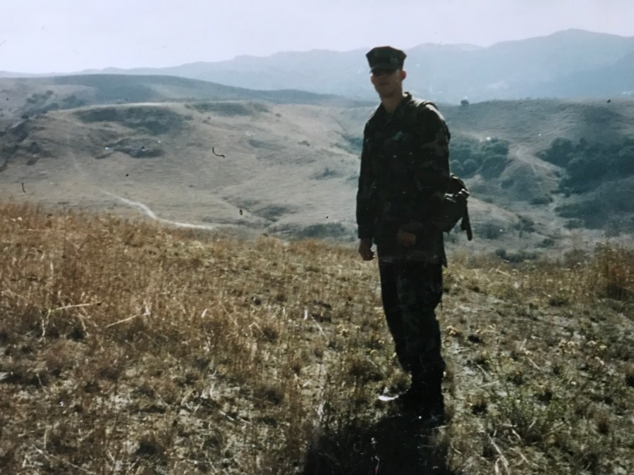 A man in military gear standing in nature.