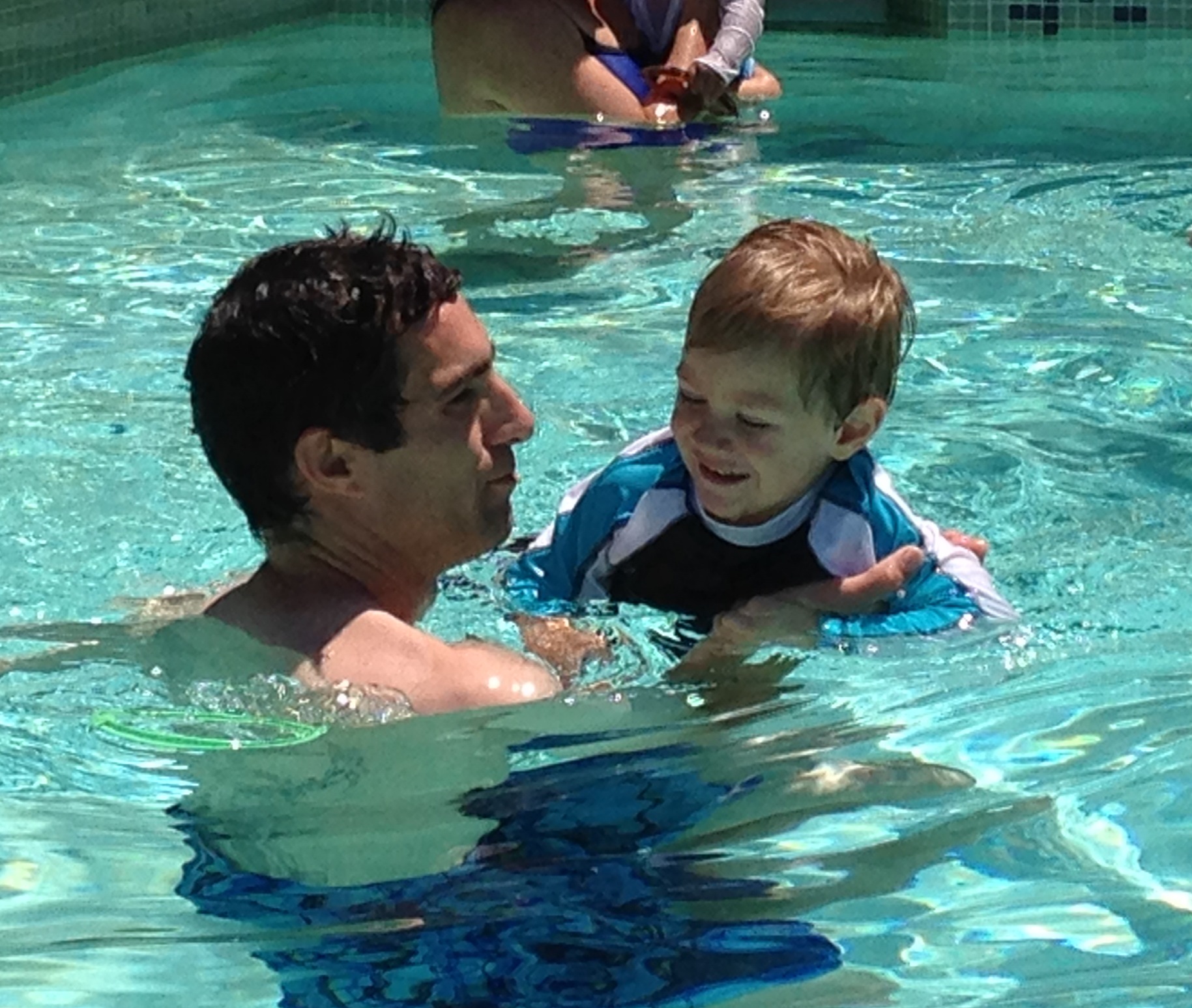 A man and a baby in a pool.