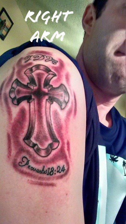 Tattoo of a cross on a shoulder.