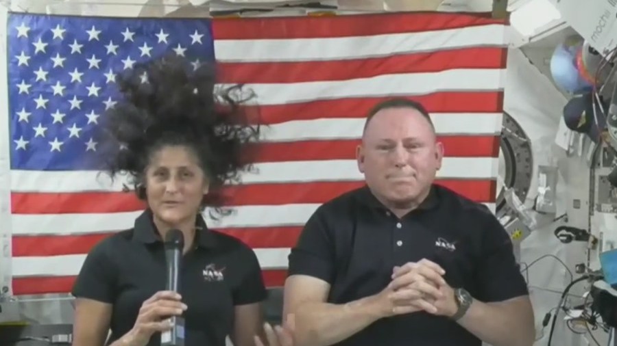 Boeing Starliner astronauts Butch Wilmore and Suni Williams, in front of an American flag aboard the International Space Station.