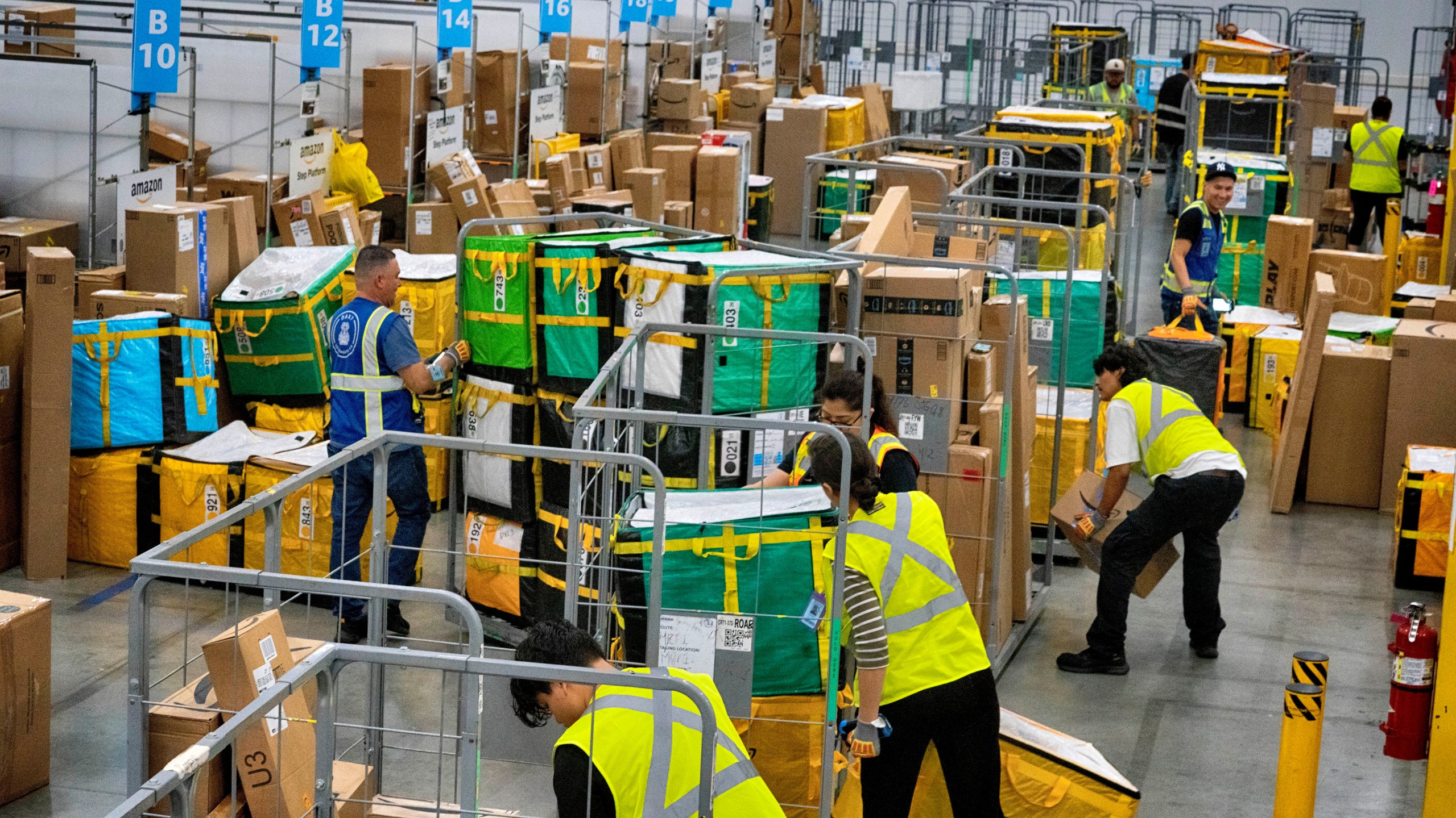 FILE - Amazon employees load packages on carts before being put on to trucks for distribution for Amazon's annual Prime Day event at an Amazon's DAX7 delivery station on July 16, 2024, in South Gate, Calif. Amazon reports earnings on Thursday, Aug. 1, 2024. (AP Photo/Richard Vogel, File)