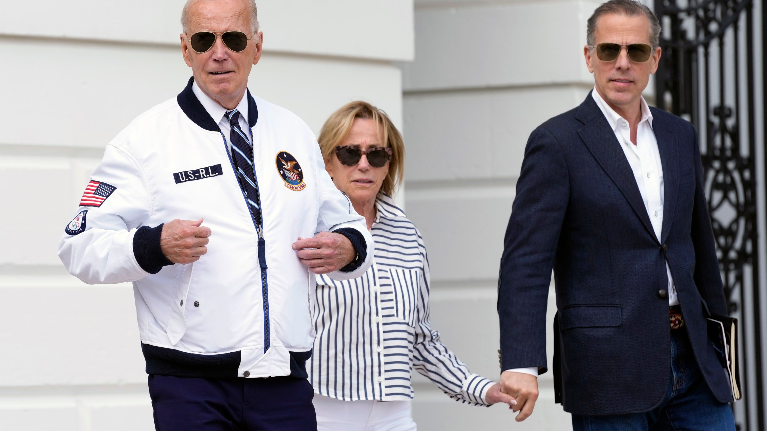 President Joe Biden, from left, walking with his sister Valerie Biden Owens and his son Hunter Biden, shows off his Team USA jacket as he walks toward Marine One on the South Lawn of the White House in Washington, Friday, July 26, 2024, en route to Camp David for the weekend. (AP Photo/Susan Walsh)