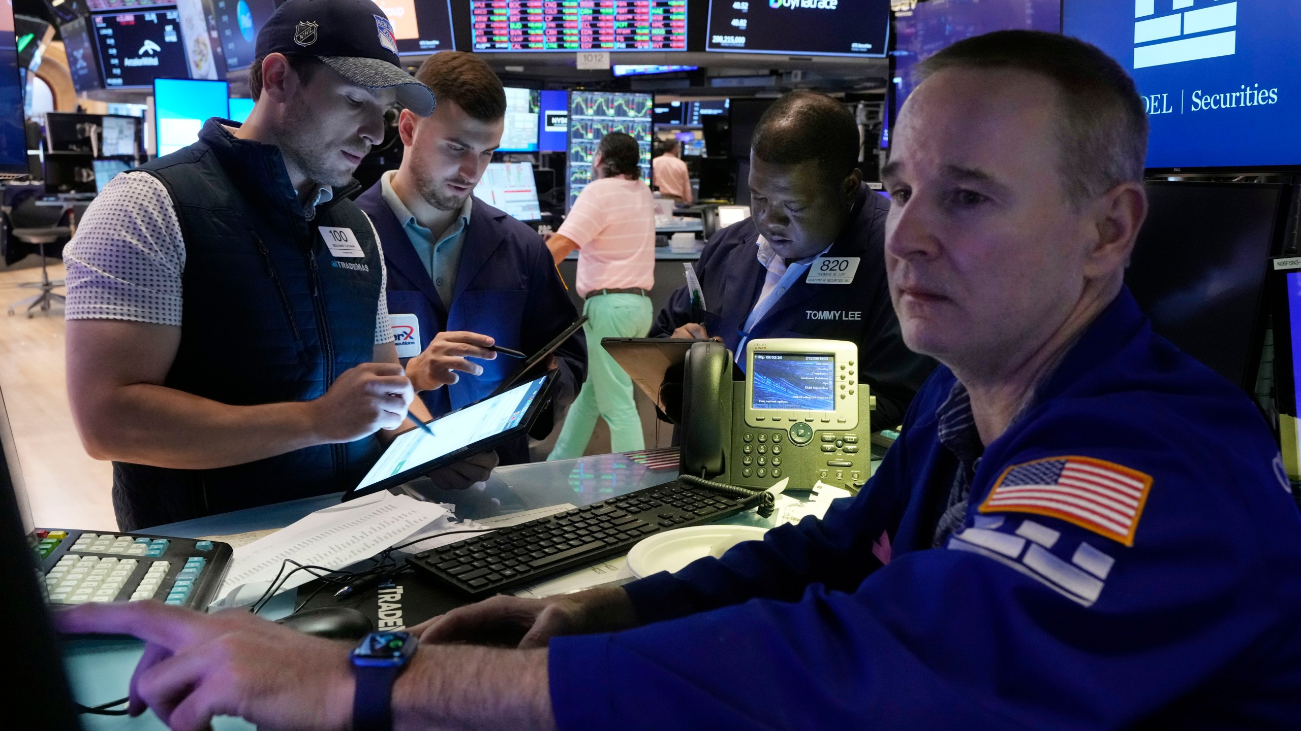 Traders gather at the post of specialist Stephen Naughton, right,on the floor of the New York Stock Exchange, Friday, Aug. 2, 2024. (AP Photo/Richard Drew)