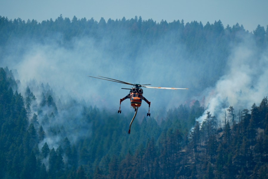 A helicopter looks to make a drop of water as the Quarry wildfire burns in the foothills near the Ken Caryl Ranch development Thursday, Aug. 1, 2024, southwest of Litteton, Colo. (AP Photo/David Zalubowski)