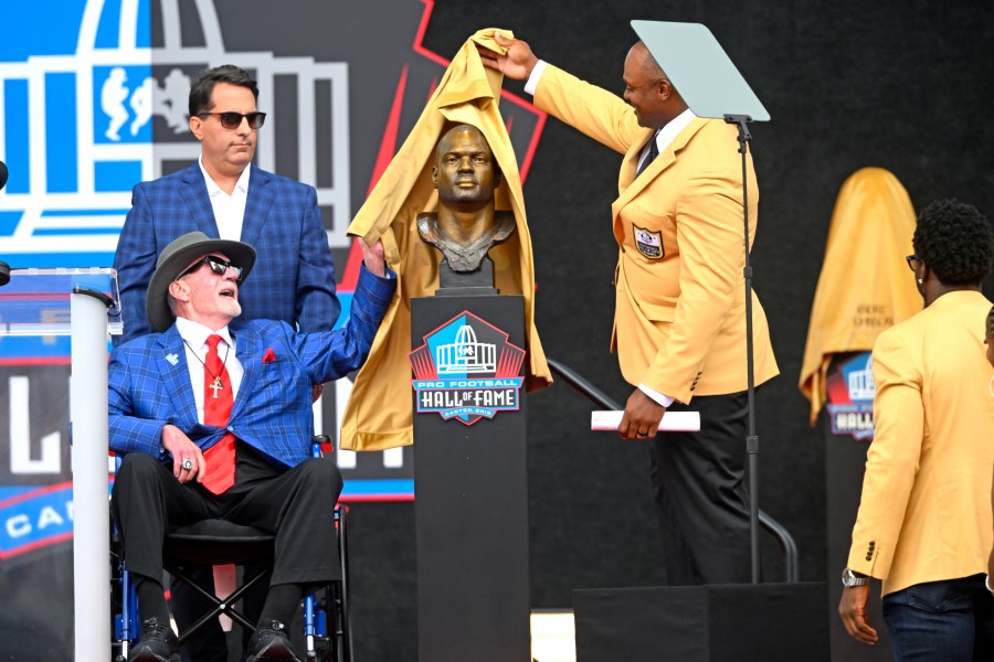 Former NFL player Dwight Freeney, second from right, and his presenter Jim Irsay, lower left, unveil his bust during an induction ceremony at the Pro Football Hall of Fame, in Canton, Ohio, Saturday, Aug. 3, 2024. (AP Photo/David Dermer)