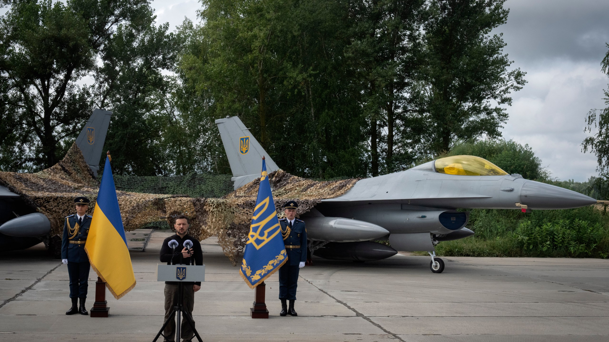 Ukraine's President Volodymyr Zelenskyy talks on the occasion of the Air Forces Day standing against the background of Ukraine's Air Force's F-16 fighter jets in an undisclosed location in Ukraine, Sunday, Aug. 4, 2024. The F-16 fighter jets that have been delivered to Ukraine by Western countries will be flying sorties in Ukrainian skies and helping the country's current fleet of Soviet-era jets to counter Russia's invasion. (AP Photo/Efrem Lukatsky)